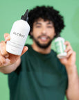 Man holding two bottles of Alcove Hair Curl Shampoo and Conditioner against a green background