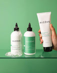 Lifestyle image of the Alcôve Curls Products with a green background including the Curls Shampoo, Conditioner and Activator