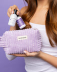 Picture of a woman holding the Alcove Mini Hydrating Shampoo and Conditioner with a purple pouch
