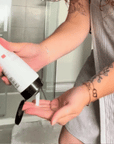 Video showing someone use the Alcove Hair Curl Activator pouring the cream on her hand in a bathroom