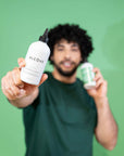 Man holding two bottles of Alcove Hair Curl Shampoo and Conditioner against a green background