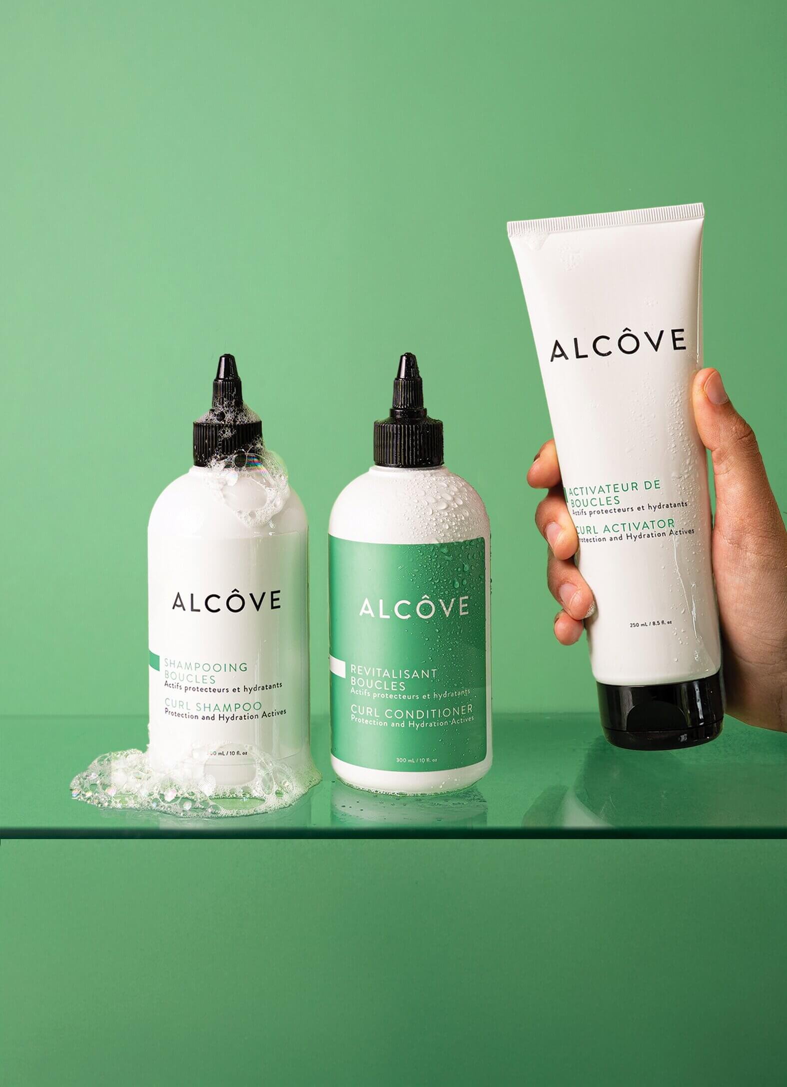 Lifestyle image of the Alcôve Curls Products with a green background including the Curls Shampoo, Conditioner and Activator
