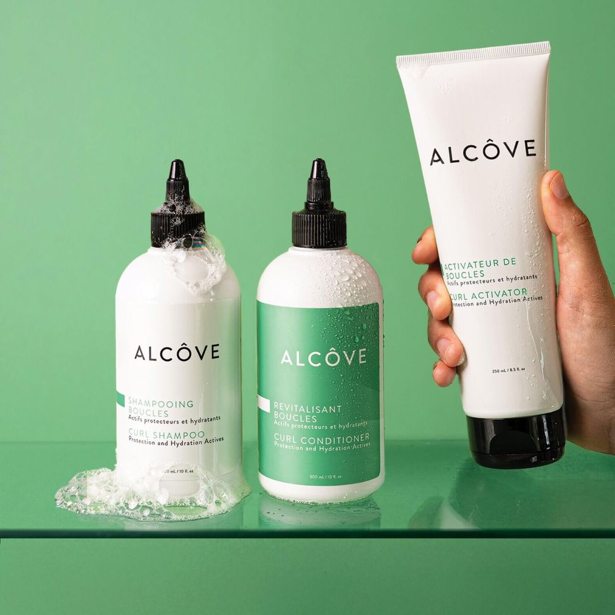 Lifestyle image of the Alcôve Curls Products with a green background including the Curls Shampoo, Conditioner and Activator