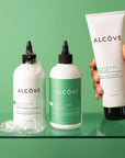 Lifestyle image of the Alcôve Curls Products with a green background including the Curls Shampoo, Conditioner and Activator