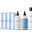 Set of Alcove hair care products including bottles and a striped pouch on a white background