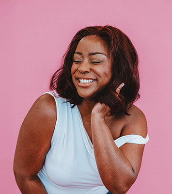 Woman with a short hairstyle smiling against a pink background