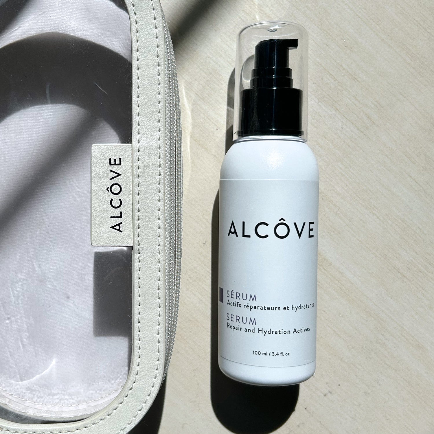 A lifestyle image of the Alcove Hair Serum 100 ml / 3.4 oz next to a Alcxove pouch