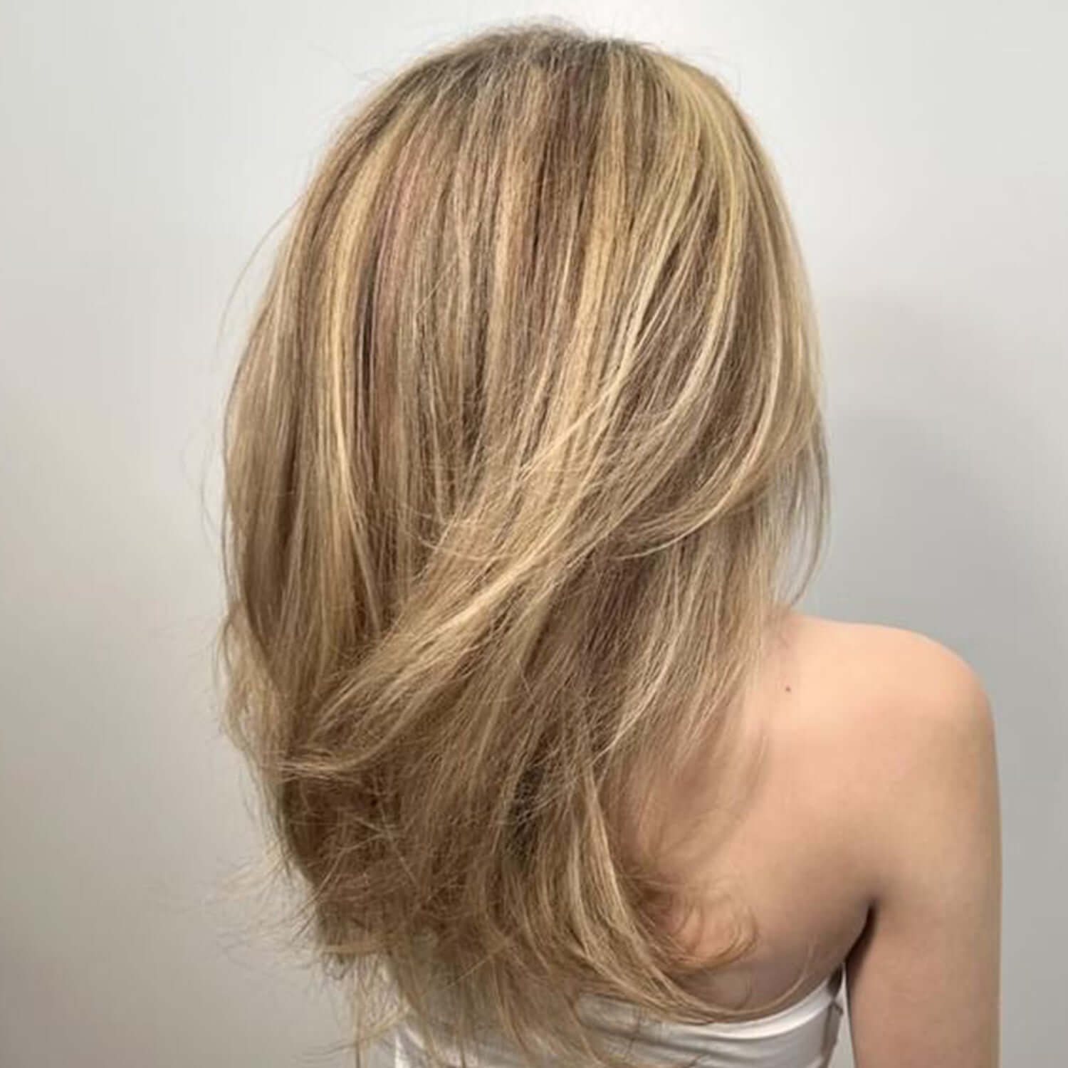 Blonde hair styled in a shoulder-length cut on a plain background after using the Alcôve Volumizing Shampoo and Conditioner